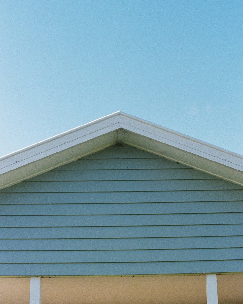 Slate-blue horizontal siding under a white-trimmed gable against a clear sky