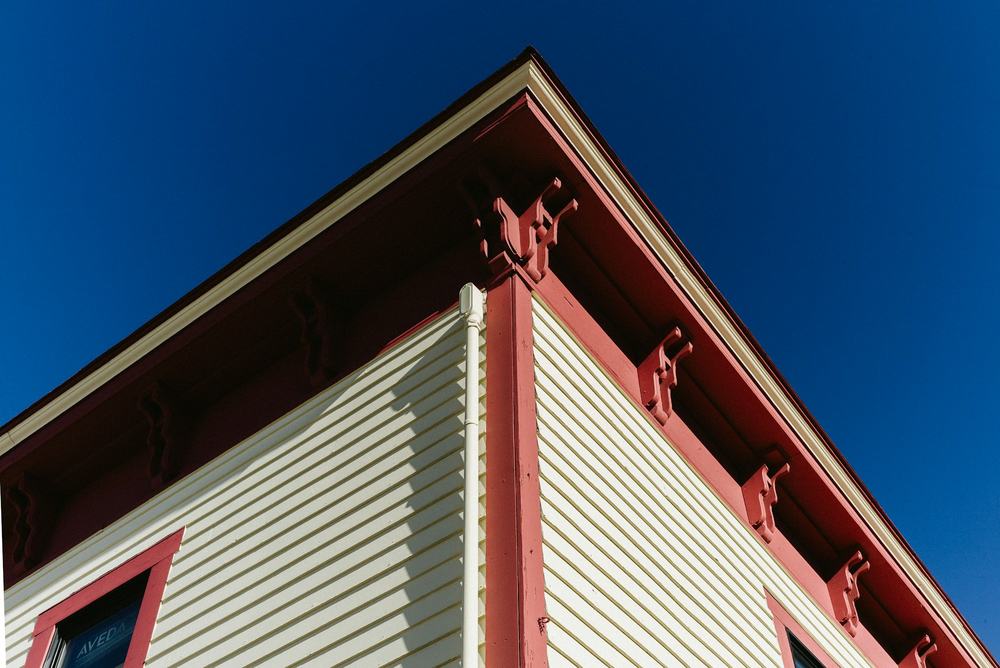 Looking up at the corner of a house where white clapboard meets red corner and roof trim